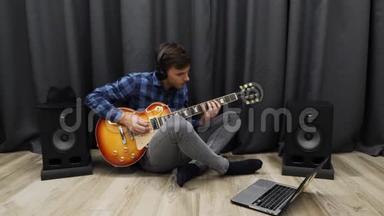 人类学习弹吉他。戴着耳机练习弹电吉他的人。年轻人一边弹吉他